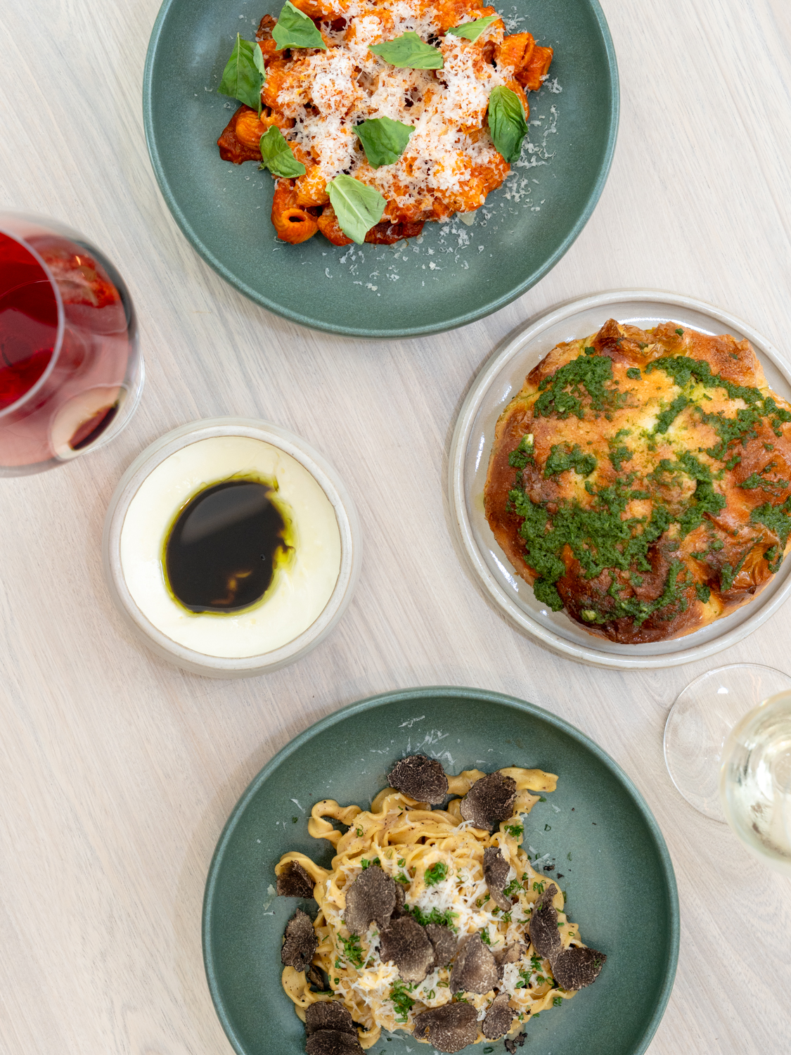 A spread of dishes at Ash including rigatoni vodka, focaccia, and pasta, paired with red and white wine